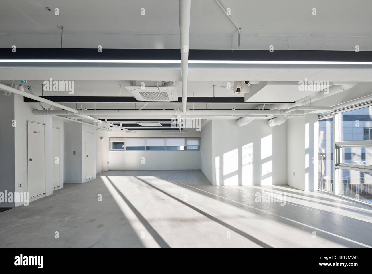 Pavimento vuoto per ufficio con soffitto a vista e luce potente per finestre. Foto Stock