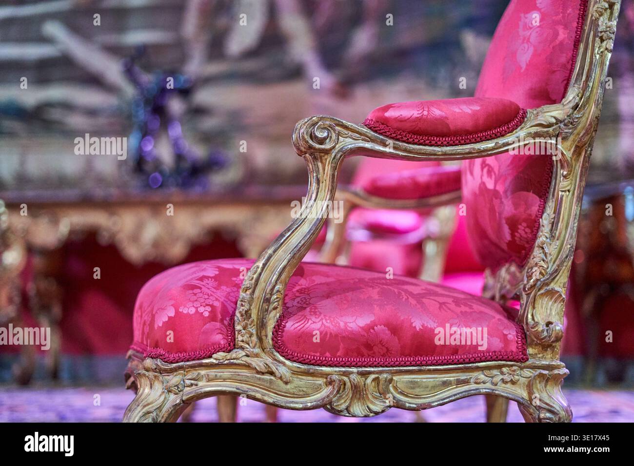 Questa fotografia ravvicinata mostra una squisita poltrona antica con decorazioni in legno a foglia oro in stile rococò o barocco... Foto Stock