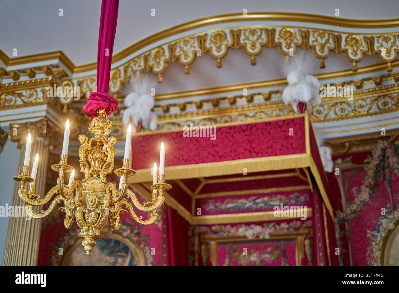 Sfarzoso interno del palazzo con lampadario dorato e letto a baldacchino decorato in stile barocco Foto Stock