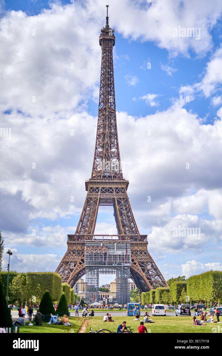 La Torre Eiffel si erge maestosamente contro un cielo blu brillante punteggiato da soffici nuvole bianche, vista dal parco Champ de Mars di Parigi... Foto Stock