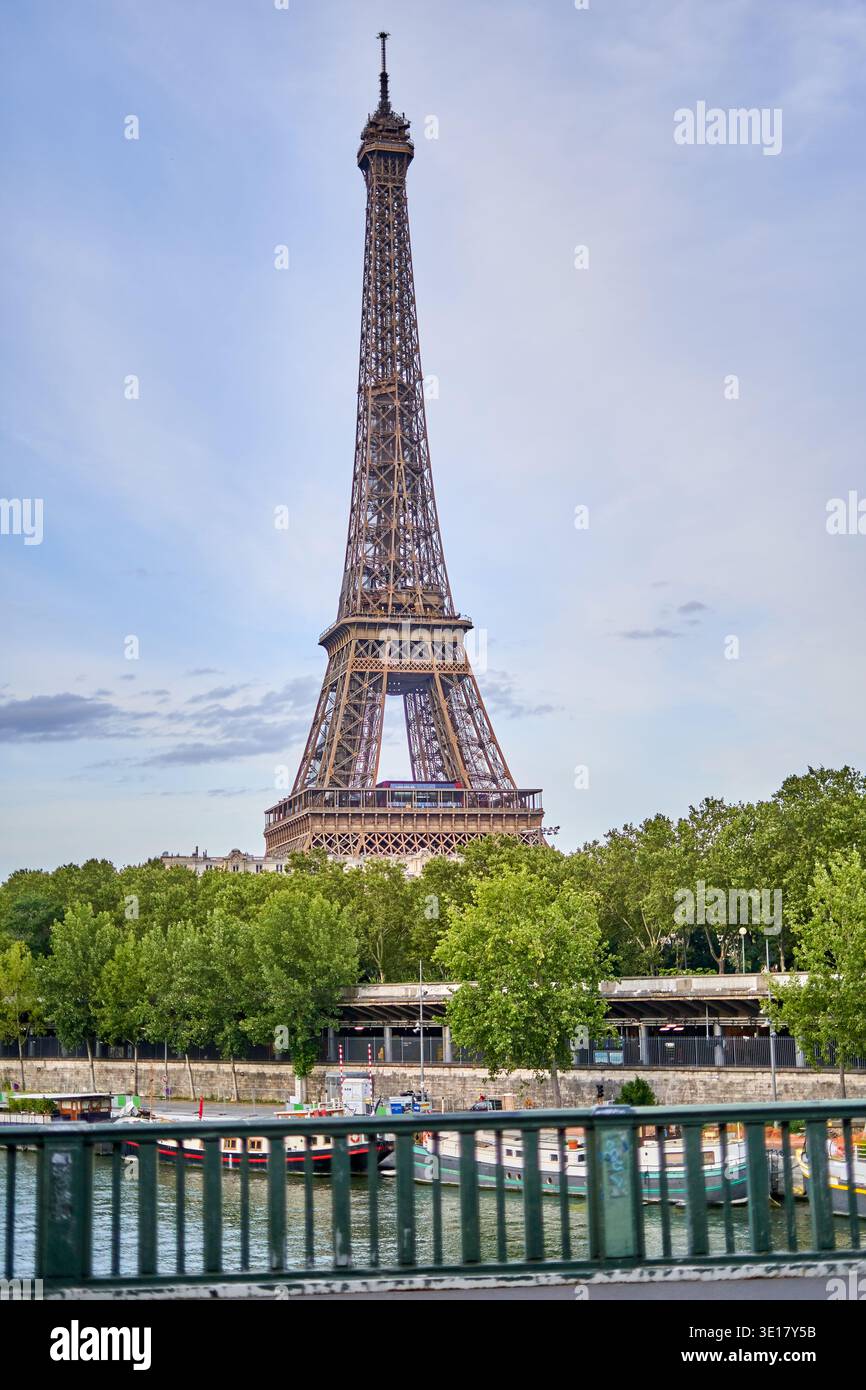 La Torre Eiffel si erge maestosamente contro un cielo parzialmente nuvoloso, visto dall'altra parte della Senna a Parigi, in Francia. L'iconico reticolo di ferro... Foto Stock