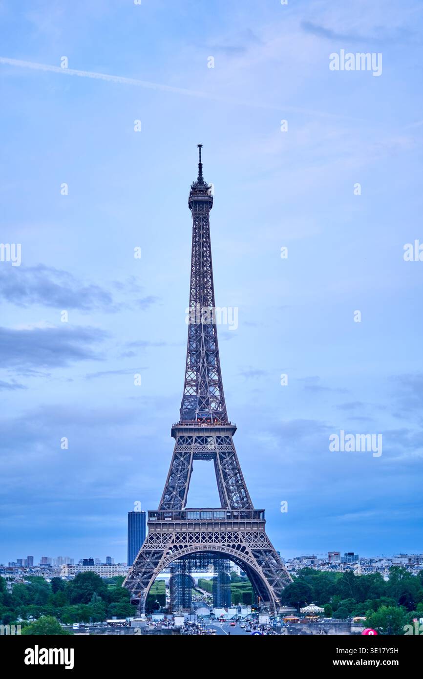 La Torre Eiffel si erge maestosamente contro un cielo blu morbido con nuvole sparse, catturate durante le ore di luce del giorno a Parigi, in Francia. Il... Foto Stock