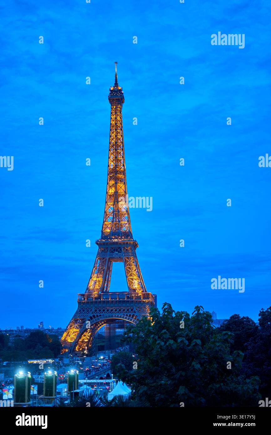 La Torre Eiffel si erge maestosamente contro un cielo notturno blu profondo, illuminato da migliaia di luci dorate che mettono in risalto il suo intricato... Foto Stock