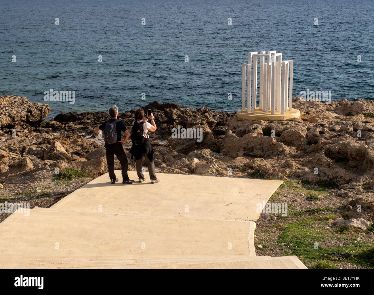 I turisti guardano l'installazione geometrica in marmo "Views of Infinity" di Harry Paspallis, che si trova vicino al sentiero costiero di Paphos, Cipro. Foto Stock