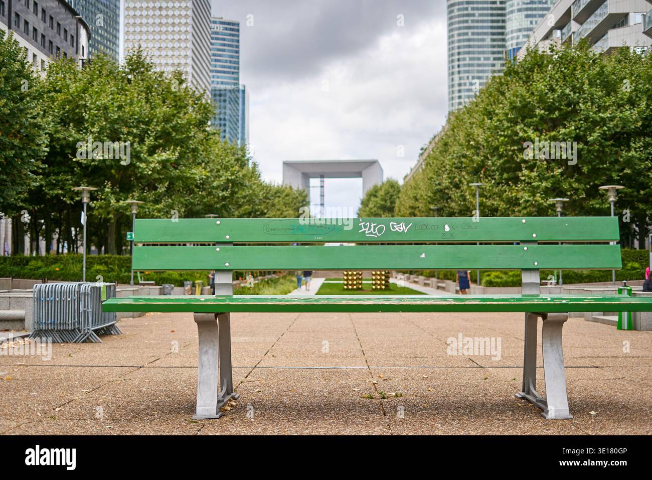Una panchina verde vivace del parco con graffiti si trova in primo piano di una moderna piazza urbana a Parigi, Francia Foto Stock