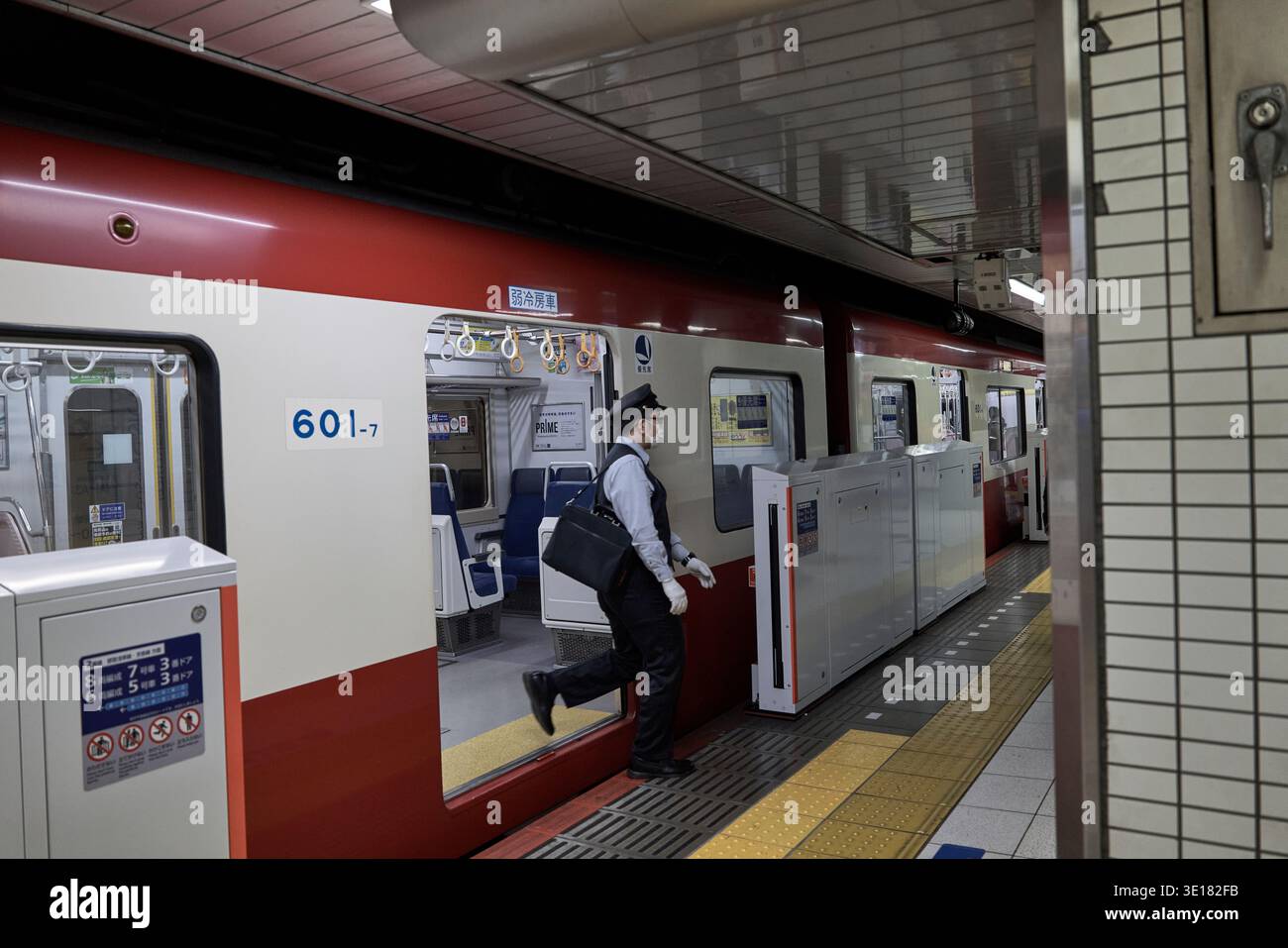 Scena della piattaforma ferroviaria con un membro del personale in uniforme accanto alla carrozza. Foto Stock