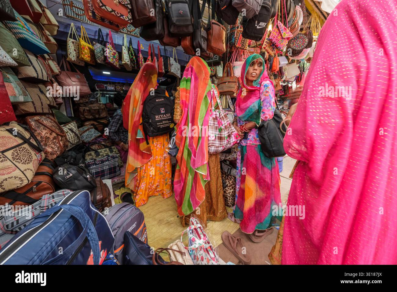 Uno stretto vicolo a Pushkar Mela è fiancheggiato da negozi che vendono vivaci borse cucite a mano, borse a mano in pelle e zaini dai motivi vivaci. Foto Stock