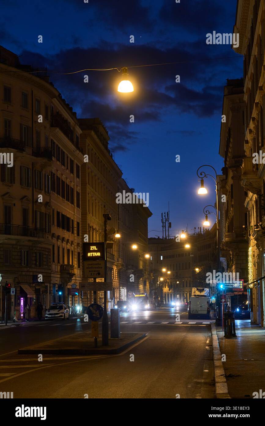 Strada romana Blue Hour con fari ed edifici storici. Foto Stock
