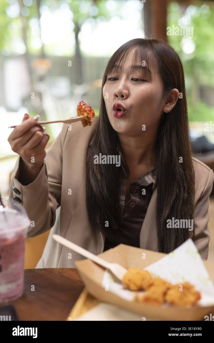 Giovane donna asiatica che mangia pollo fritto Foto Stock