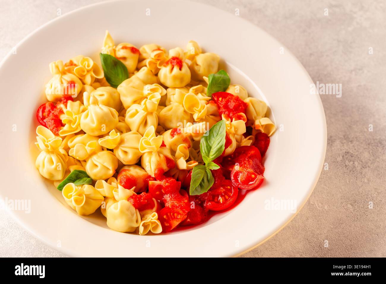 Pasta ripiena italiana. Sacсhettini pasta in un piatto con salsa di pomodoro. Foto Stock