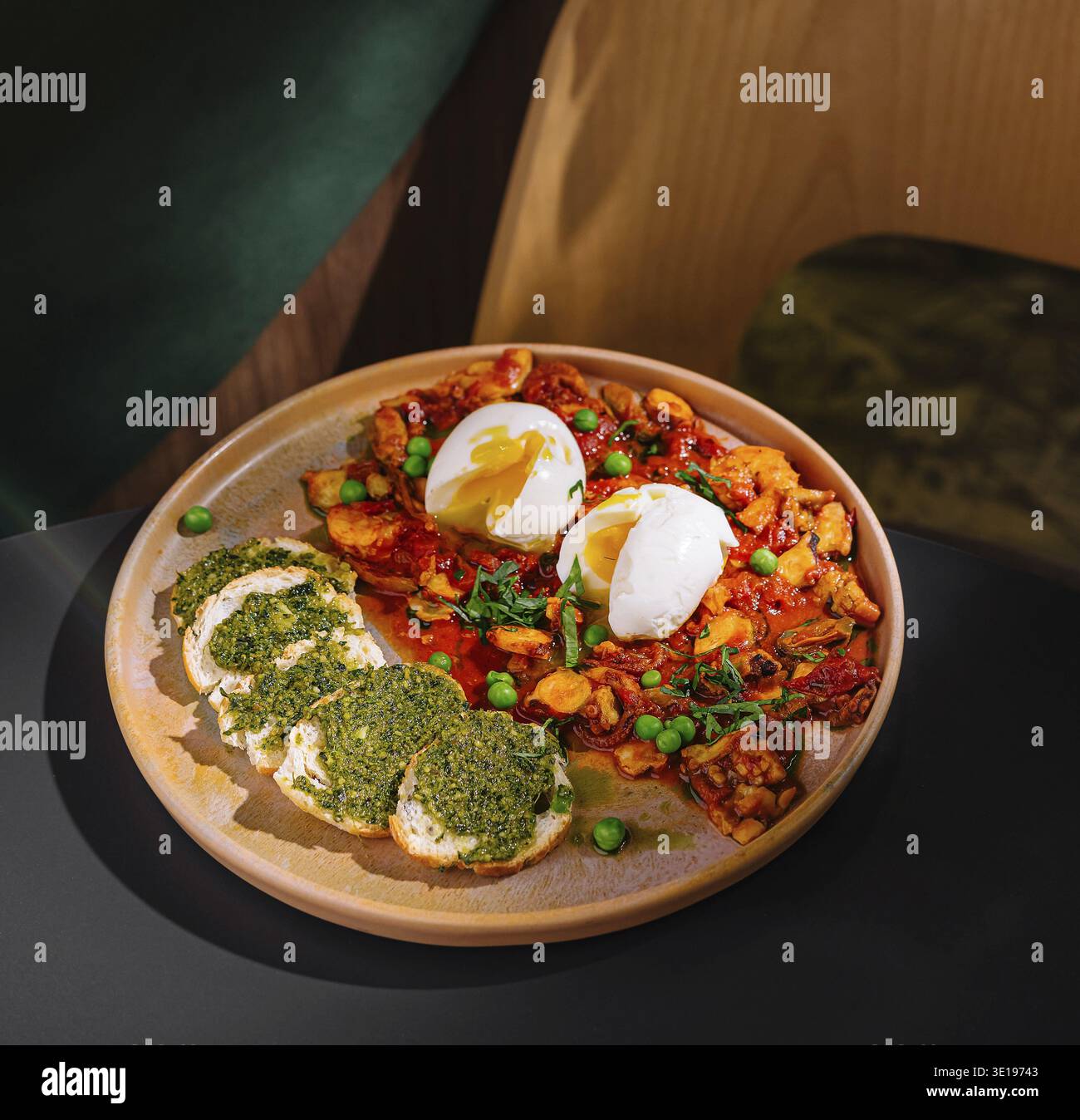 Moderno caffè che serve un pasto delizioso e salutare di shakshuka con uova in camicia e bruschetta al pesto Foto Stock