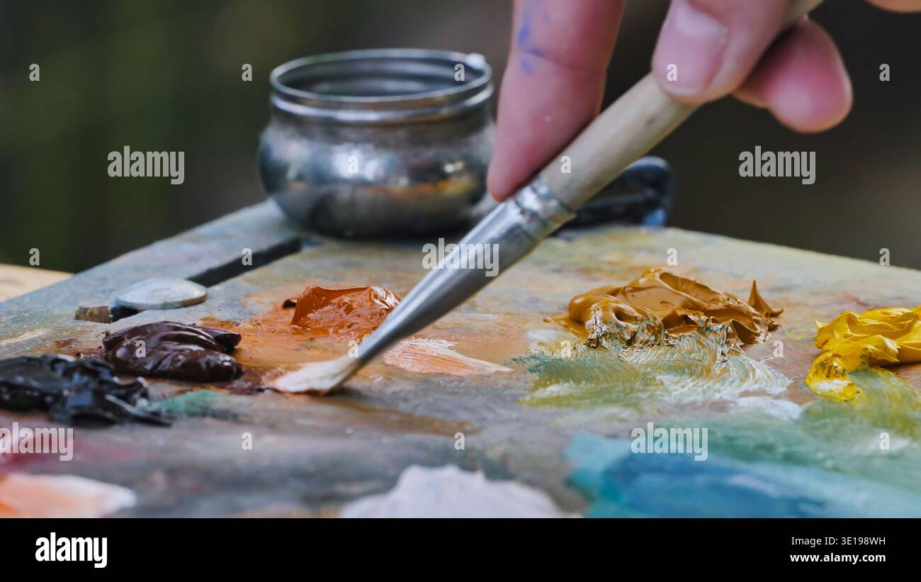 Pittore che mescola vernici a olio su palette con pennello nello nello studio d'arte Foto Stock