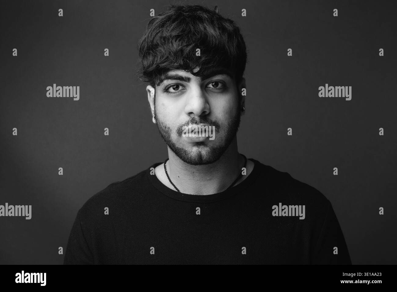 Studio shot di giovani bello barbuto uomo indiano contro lo sfondo grigio in bianco e nero Foto Stock