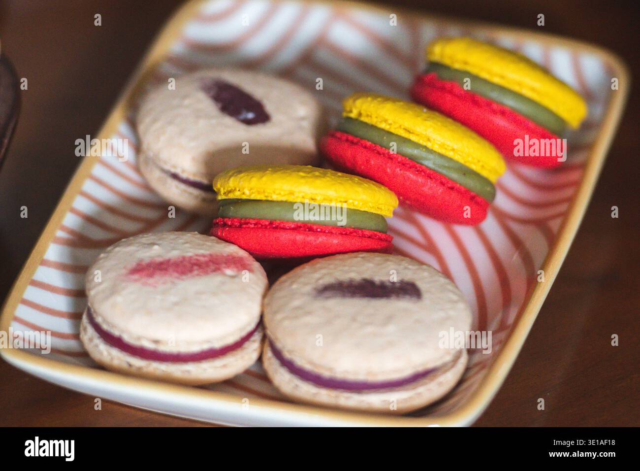 Primo piano di macaron colorati disposti su un vassoio di ceramica con colori giallo, verde e rosso ispirati alla bandiera lituana Foto Stock