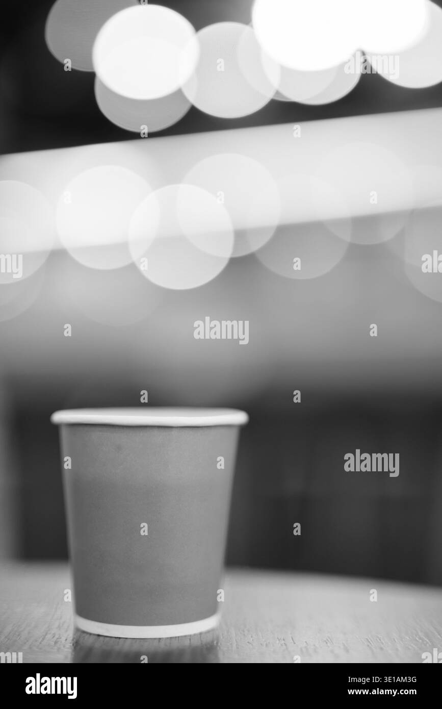 Caffè caldo nel bicchiere di carta poste sul tavolo di legno all'interno del coffee shop con spazio di copia in bianco e nero Foto Stock