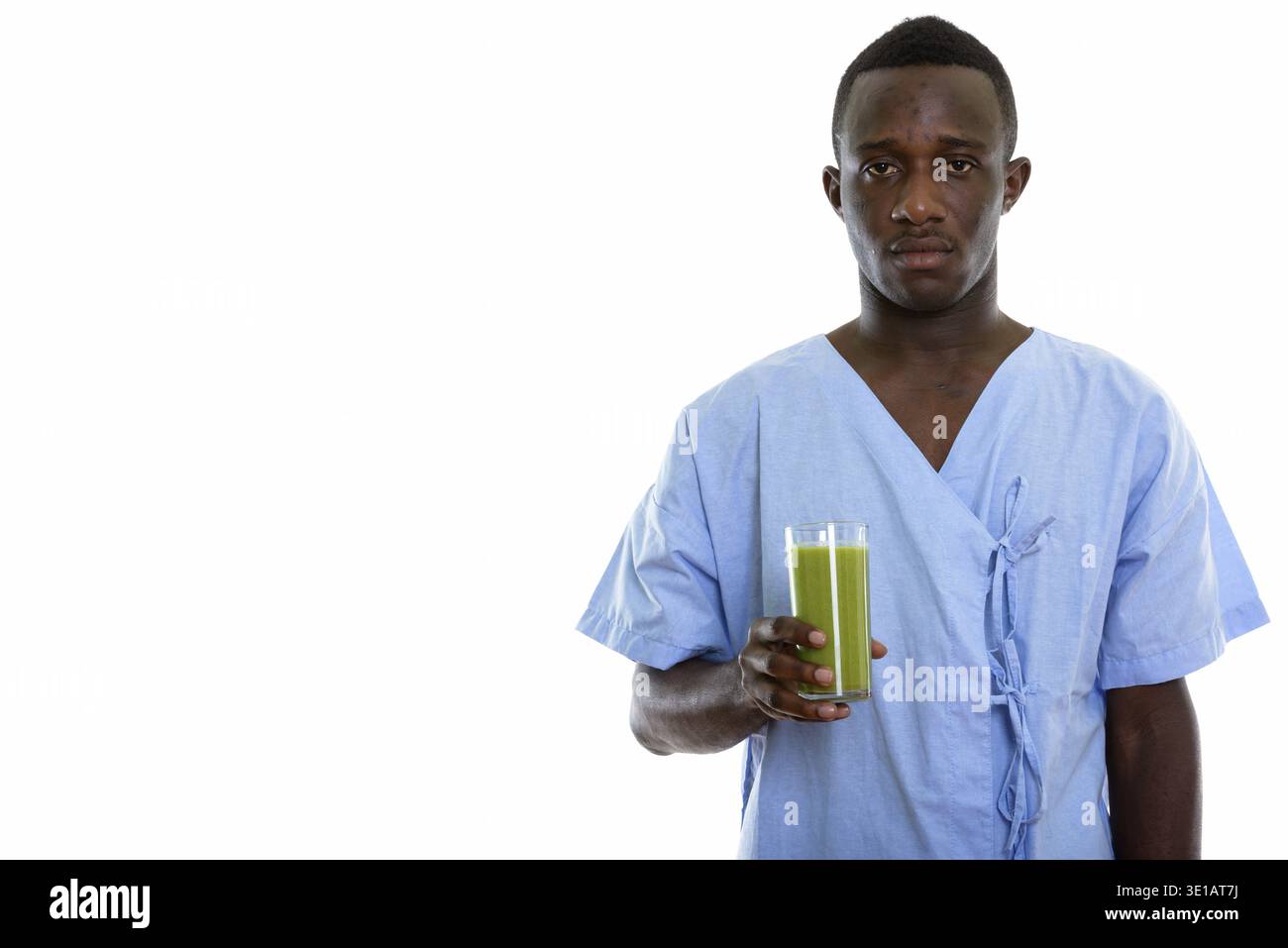 Studio shot del giovane africano nero uomo paziente tenendo un bicchiere di verde frullato vegetale Foto Stock