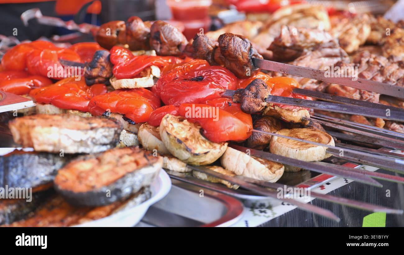 Venditrice di cibo di strada che prepara verdure alla griglia e spiedini di carne Foto Stock