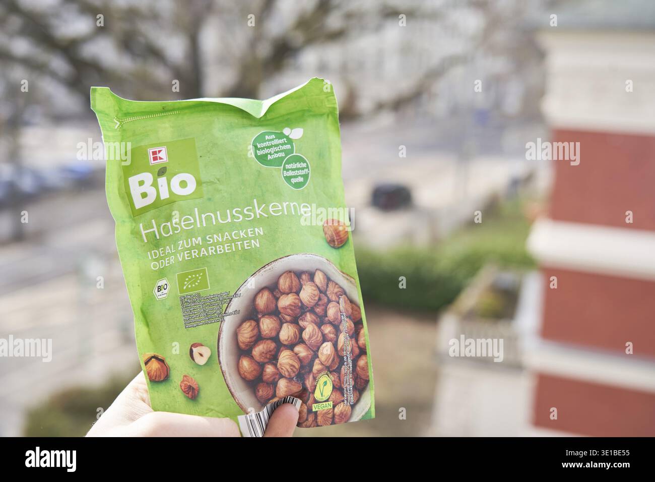 Confezione di nocciole biologiche con una mano, etichetta verde, fondo sfocato, K-Bio, Kaufland Bio, biologiche, nocciole Foto Stock