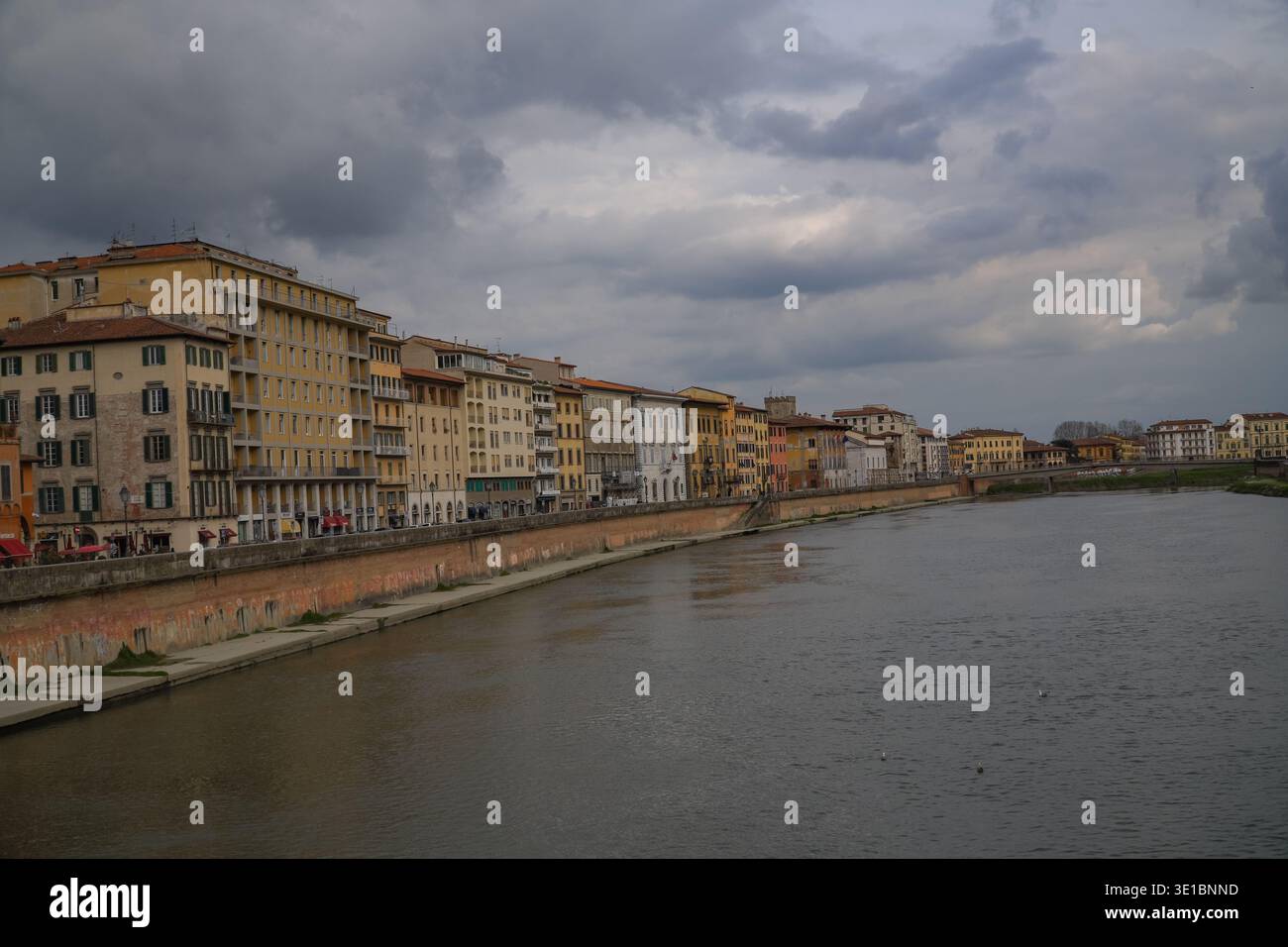 Le rive del fiume Arno a Pisa, Italia. Fila di colorati edifici medievali e rinascimentali sotto il suggestivo cielo grigio. Foto Stock