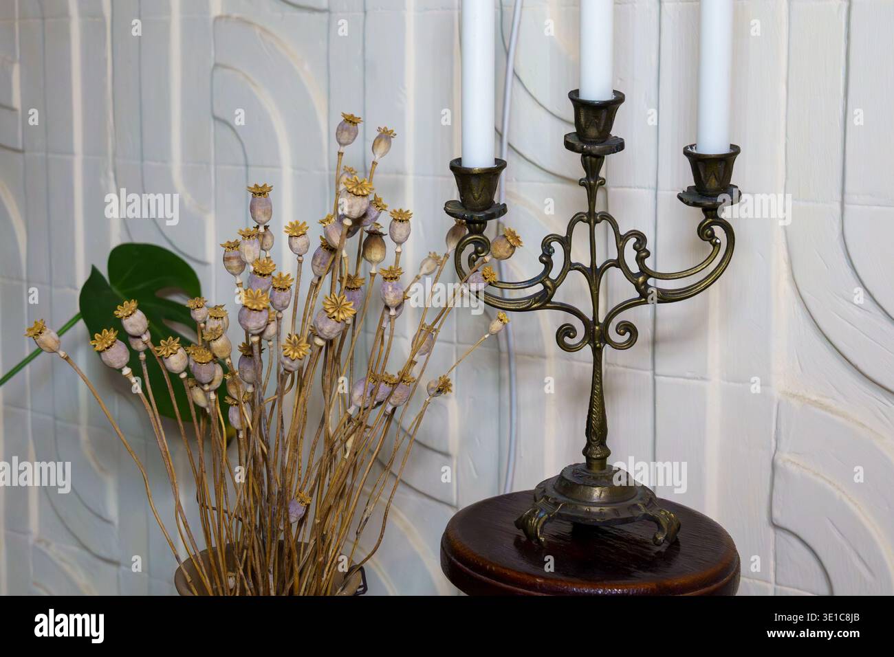 Un candelabro e steli di papavero asciutti decorano un interno antico Foto Stock