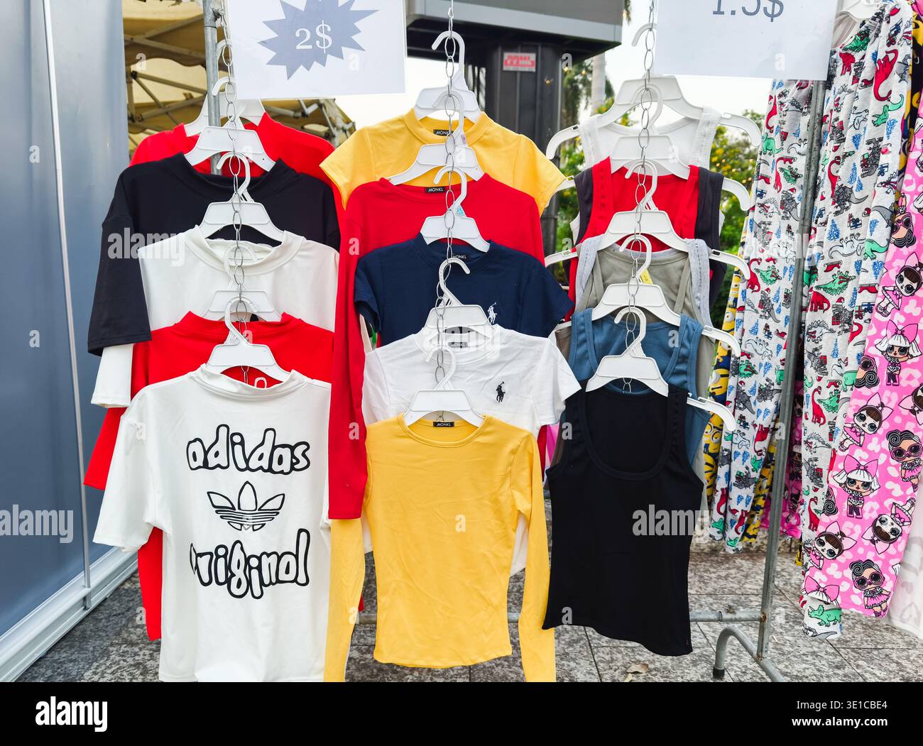 Stalla di abbigliamento con varie t-shirt, tra cui top con il logo del marchio Adidas e polo, prezzo $2. Phnom Penh, Cambogia Foto Stock