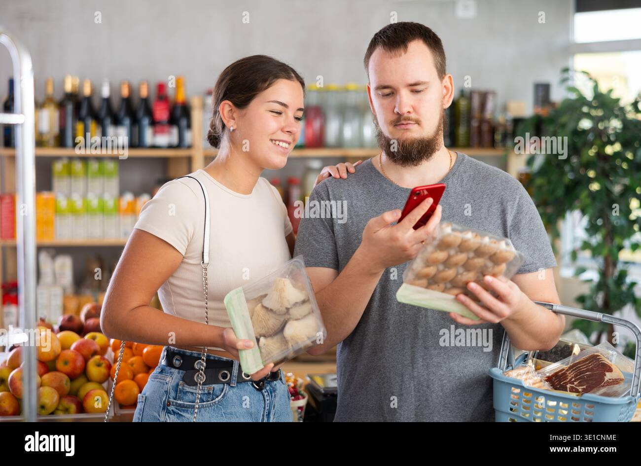 Coppia acquirente che esegue la scansione del codice QR o del codice a barre dei funghi nel supermercato Foto Stock