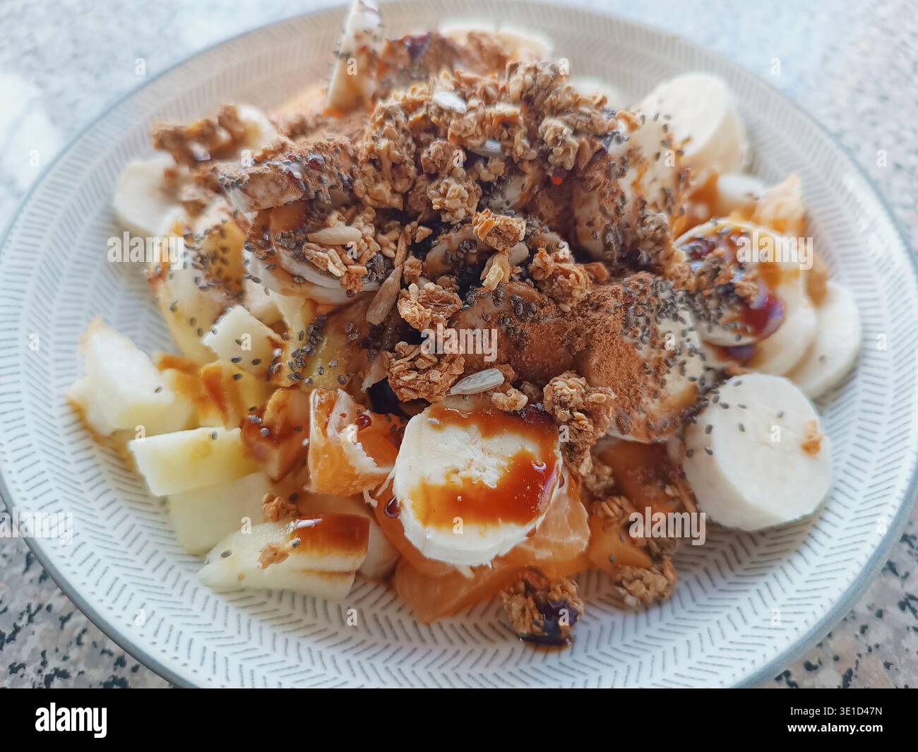 Ciotola della colazione piena di frutta fresca, granola croccante e semi di chia superfood, conditi con sciroppo Foto Stock