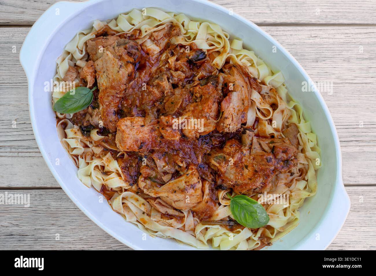 Le tagliatelle con ragù di pollo sono servite in un grande piatto ovale bianco. La pasta è condita con una salsa ricca e grossa con teneri pezzi di pollo Foto Stock
