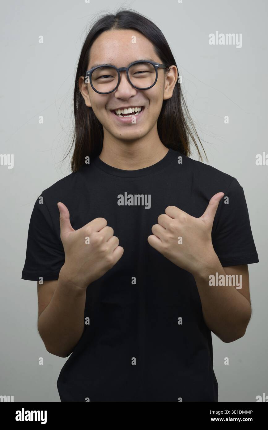 Foto in studio di un giovane asiatico con lunghi capelli su sfondo bianco Foto Stock