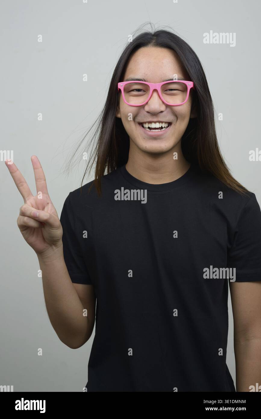 Foto in studio di un giovane asiatico con lunghi capelli su sfondo bianco Foto Stock