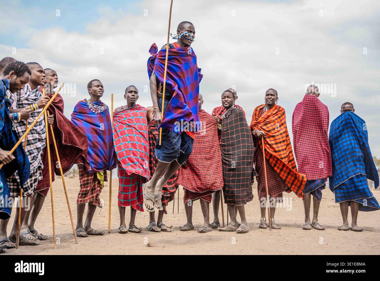 I guerrieri Maasai eseguono la tradizionale cerimonia di salto Adumu in Tanzania, con un guerriero che salta in alto sopra il cerchio degli anziani e dei giovani. Foto Stock
