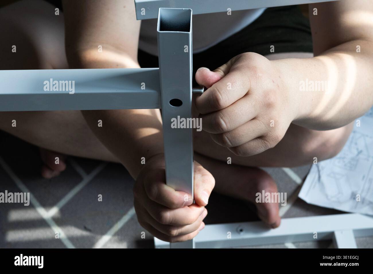 Uomo che assembla il telaio di mobili in metallo con mani e cacciavite, fai da te per migliorare la casa Foto Stock