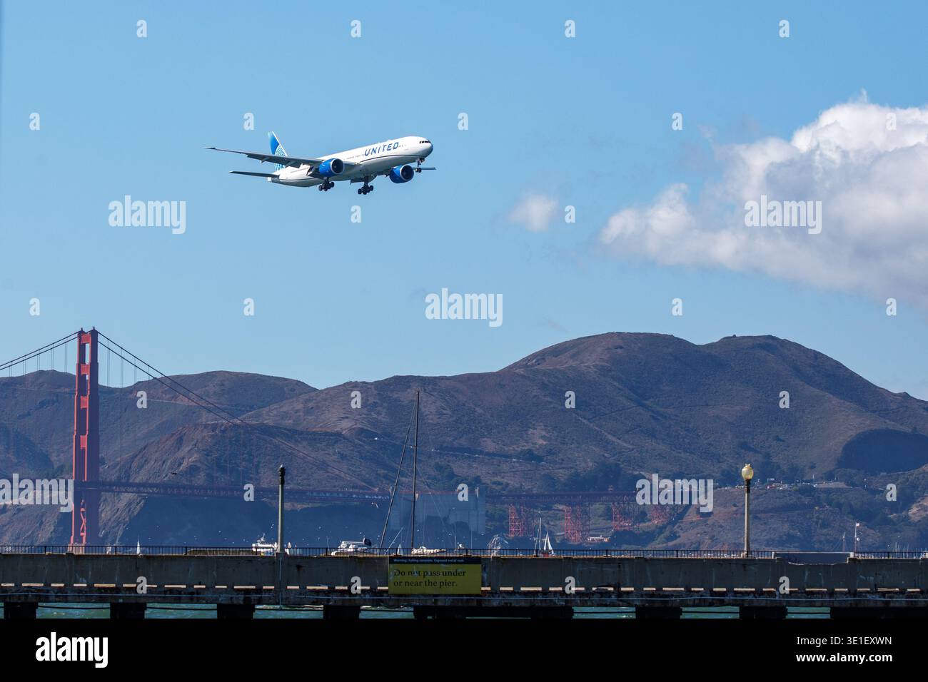 Un Boeing 777 della United Airlines vola sopra il Golden Gate Bridge a San Francisco, California, mentre si avvicina per atterrare a San Francisco in Foto Stock