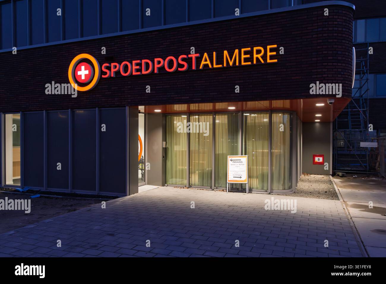 Ingresso illuminato del centro medico di emergenza Spoedpost Almere di notte, che fornisce servizi sanitari urgenti nella città di Almere, Paesi Bassi. 1 Foto Stock