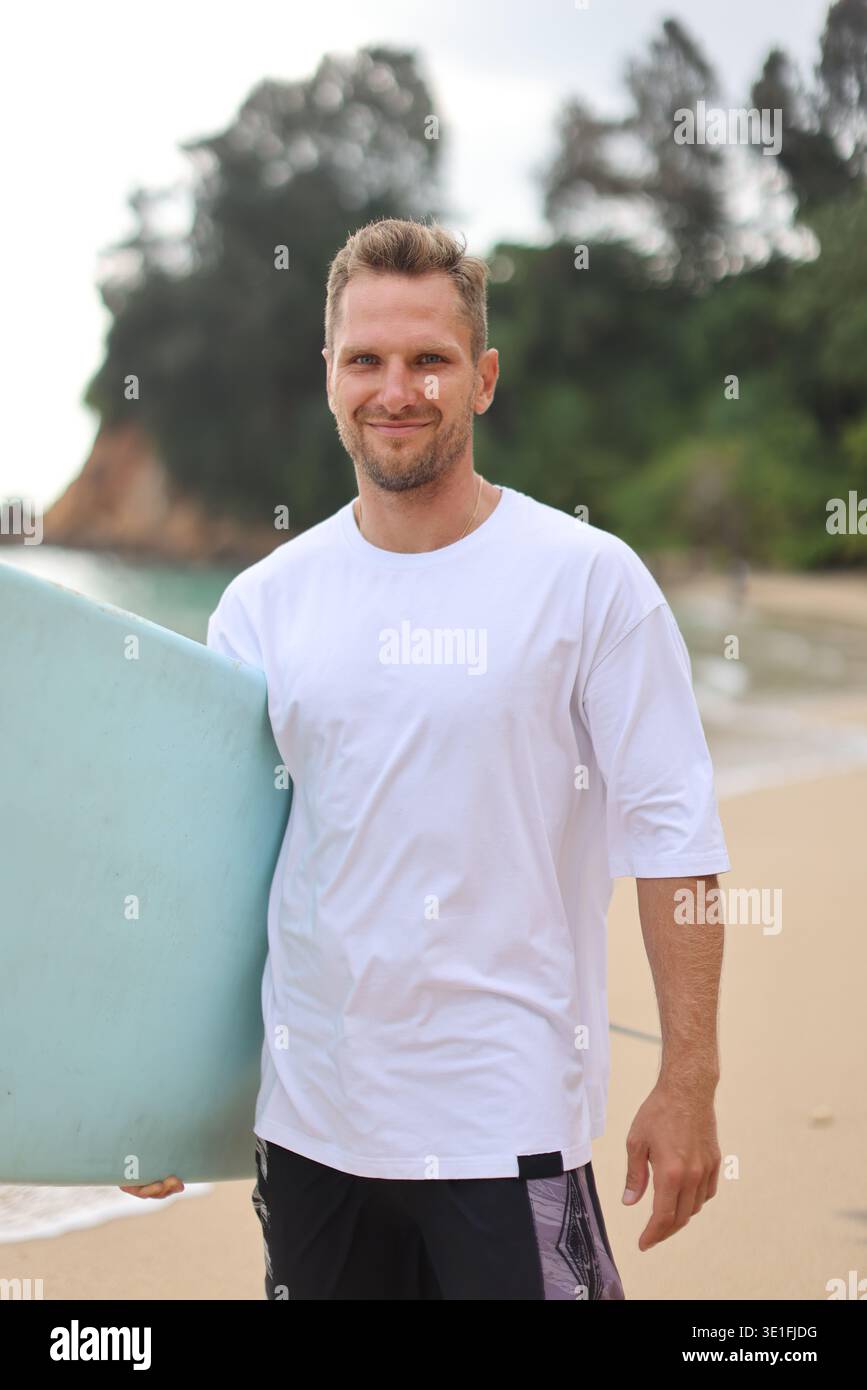 Immagine casual Beach Surfer. Ambiente luminoso da spiaggia con calmo Surfer con tavola da surf e abbigliamento casual Foto Stock