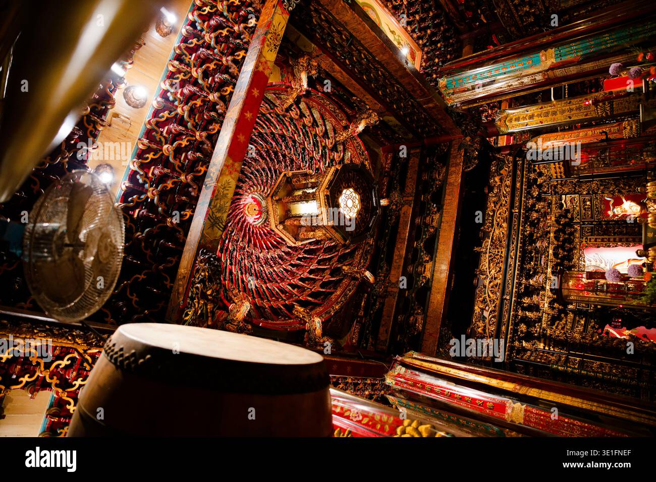 Primo piano del soffitto decorato nel Tempio di Longshan, con intricate incisioni rosse e oro, lanterne radianti e una calda illuminazione ambientale. Foto Stock