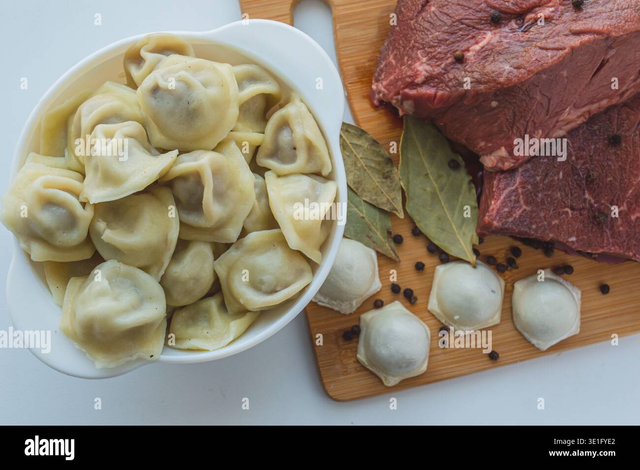 Un pezzo di carne di manzo e gnocchi di manzo su un tavolo da cucina. Uno striscione con prodotti a base di carne marmorizzati di manzo grani di pepe e foglie di alloro. Foto di alta qualità Foto Stock