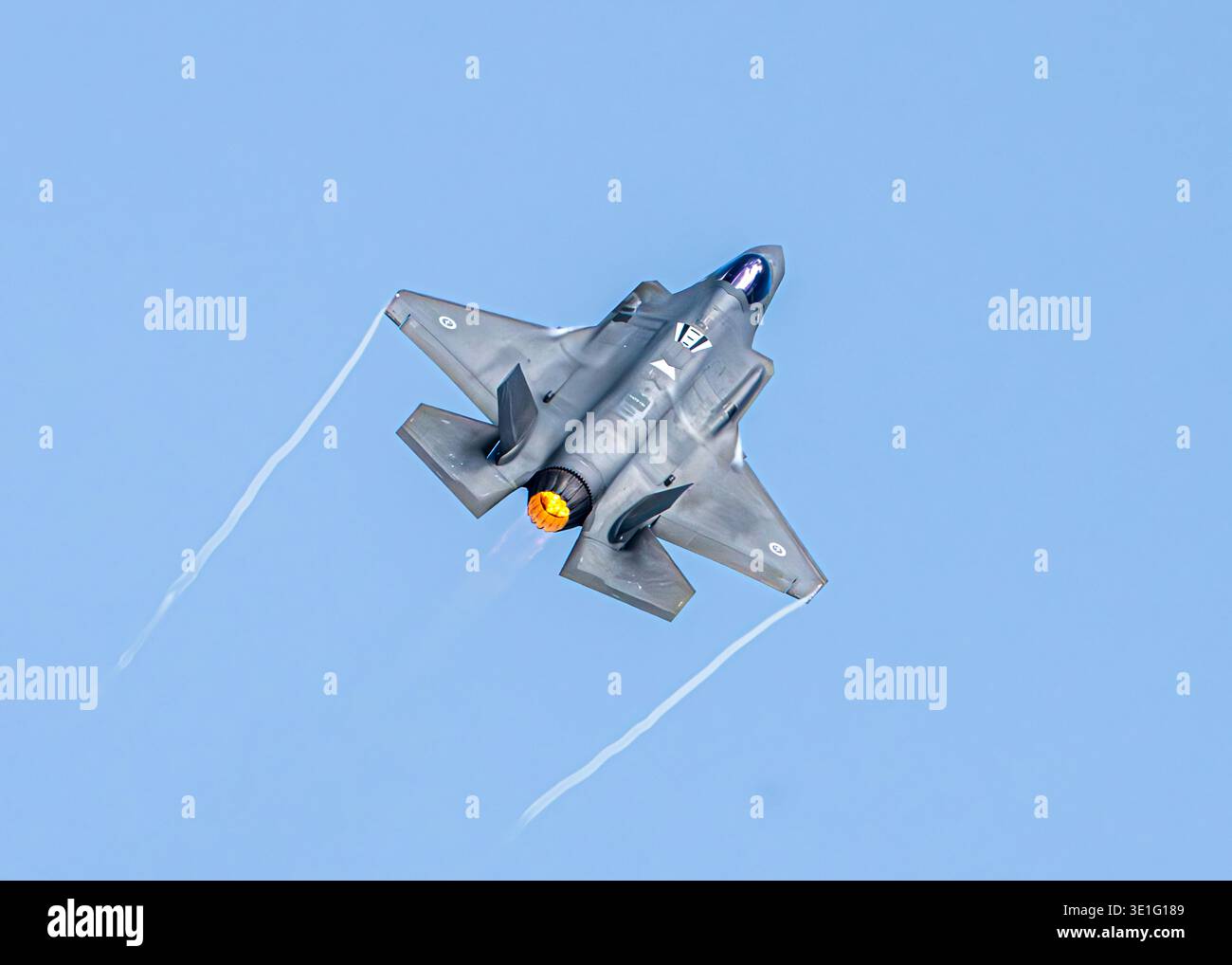 Veduta aerea di un potente jet militare che vola attraverso un cielo azzurro, lasciando dietro le quinte bianche, Singapore. Foto Stock