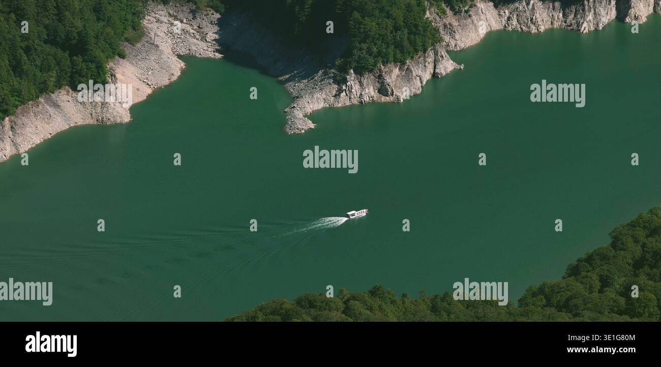 Lago blu verdastro con pendii rocciosi boscosi Foto Stock