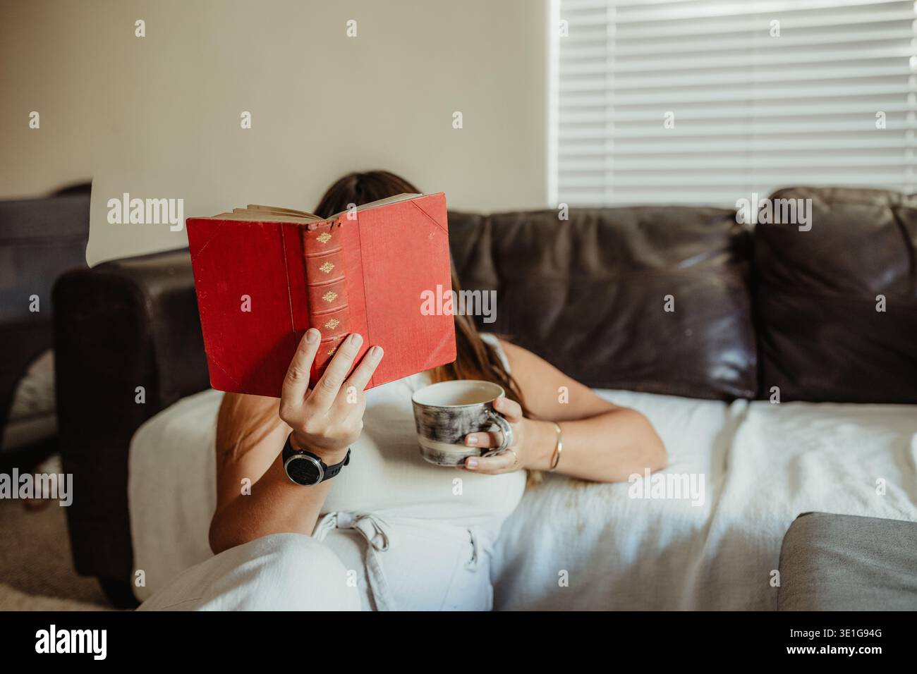 Donna che legge un libro d'epoca seduto sul pavimento a casa Foto Stock