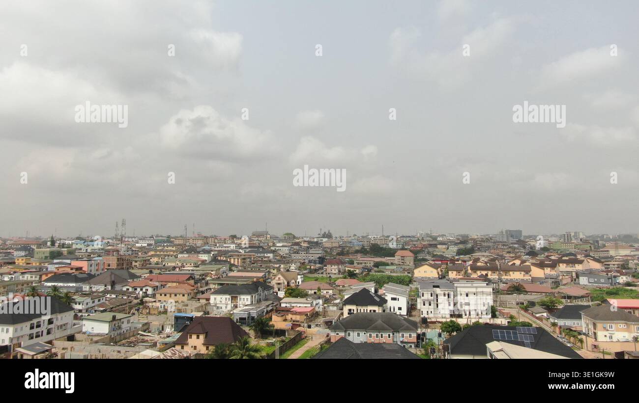 Una strada urbana strutturata a Lagos, Nigeria, che mostra veicoli in movimento e flusso di traffico regolare accanto a campi verdi paesaggistici, alberi ed edifici moderni. Foto Stock