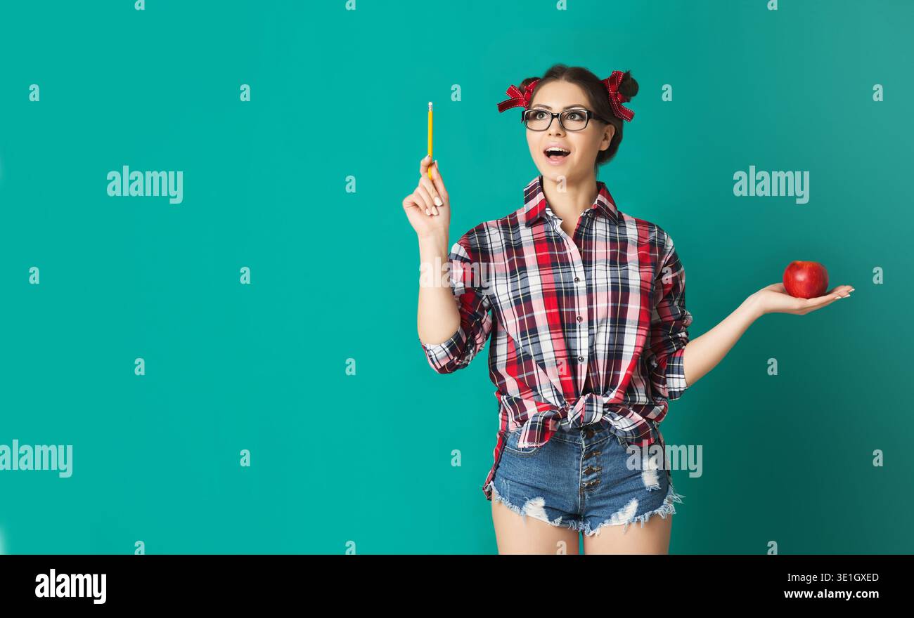Bella ragazza di moda che ha idea, che tiene la mela sopra il blu Foto Stock
