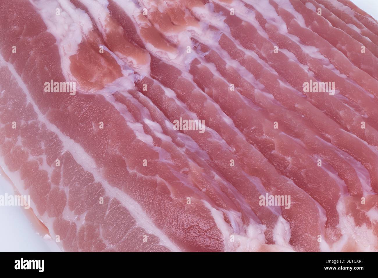 Sezioni di bacon raw Studiolit dettagliate. Immagine ravvicinata del bacon rosa grezzo con striature di grasso. Foto dettagliata di bacon rosa crudo che mette in risalto grasso e mus Foto Stock