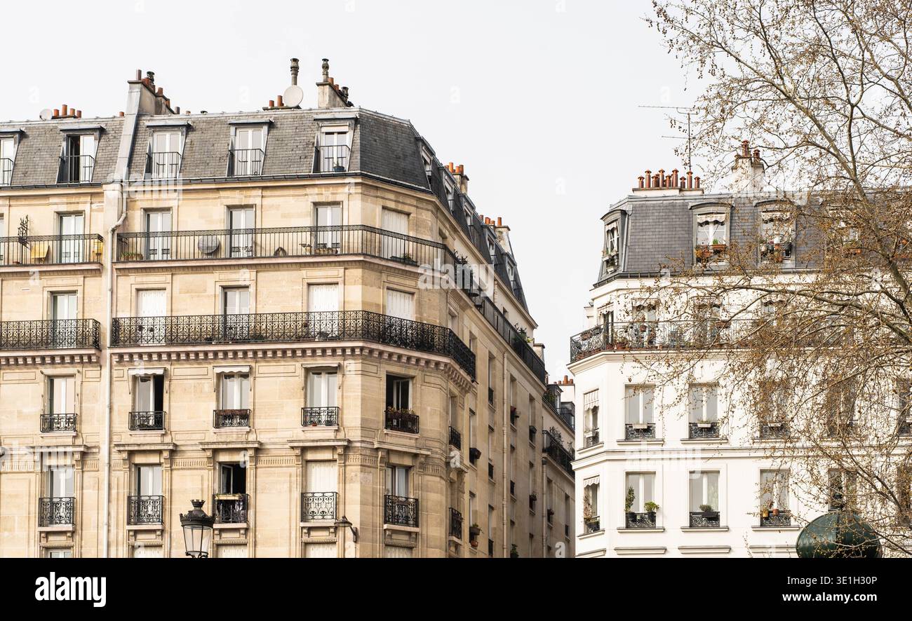 Edifici residenziali parigini classici con eleganti balconi e tetti in mansarda. L'architettura europea senza tempo è stata catturata in una tranquilla strada cittadina a par Foto Stock