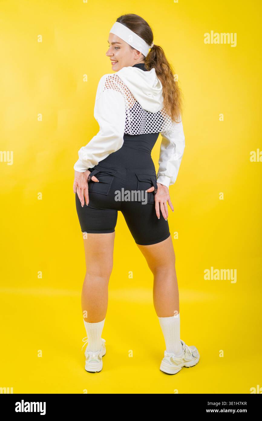 Giovane donna in posa con un abbigliamento sportivo sorridente sulla spalla Foto Stock