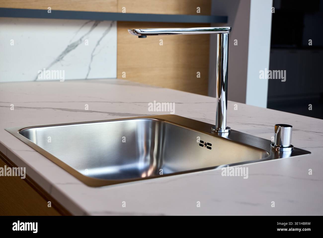 Installazione di fascia alta con lavello in acciaio inox installato su una superficie in marmo bianco. Piatto singolo rettangolare con finitura spazzolata elegante, cromato a forma di L Foto Stock