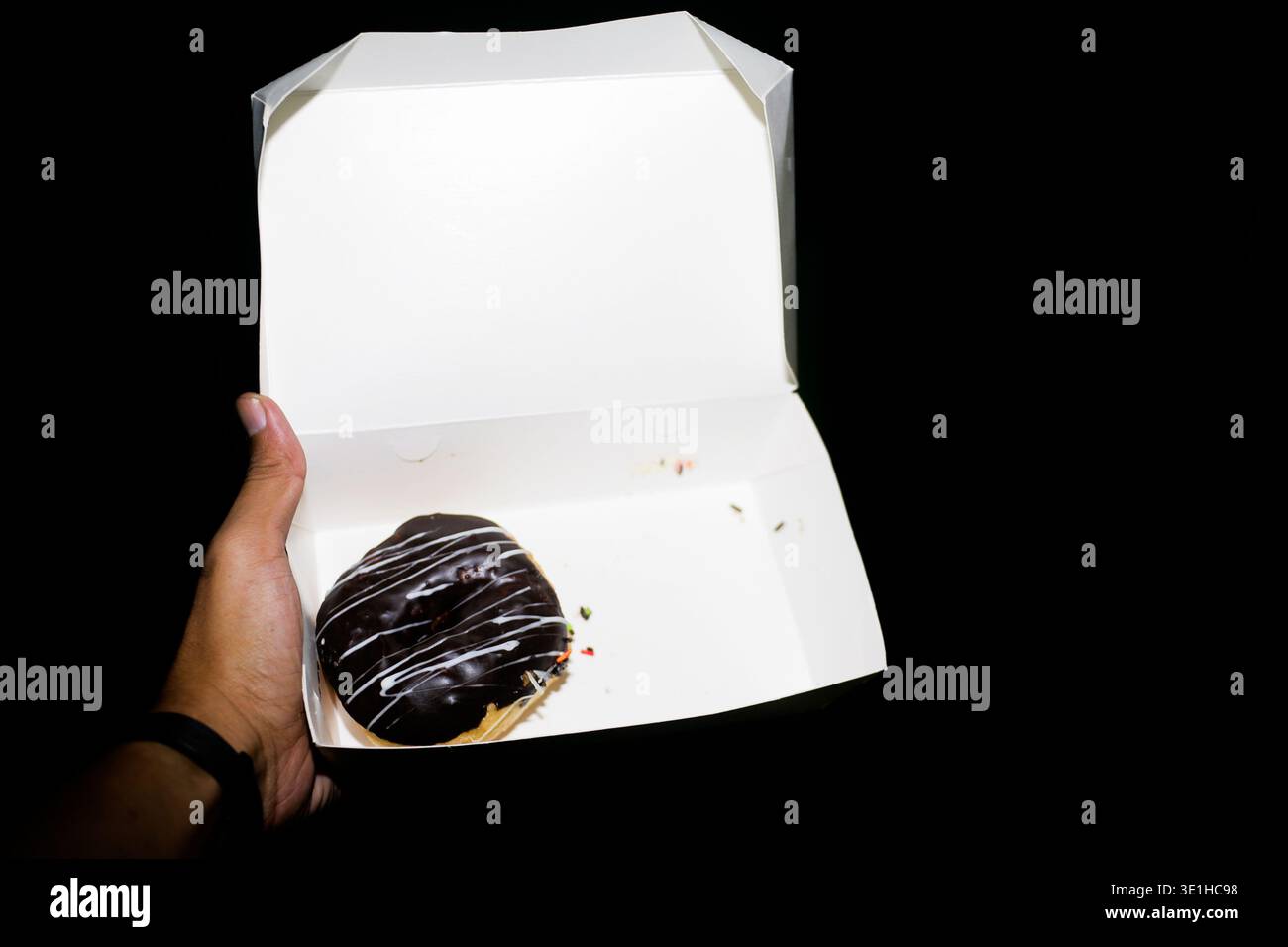 primo piano della mano che tiene una scatola di ciambella Foto Stock