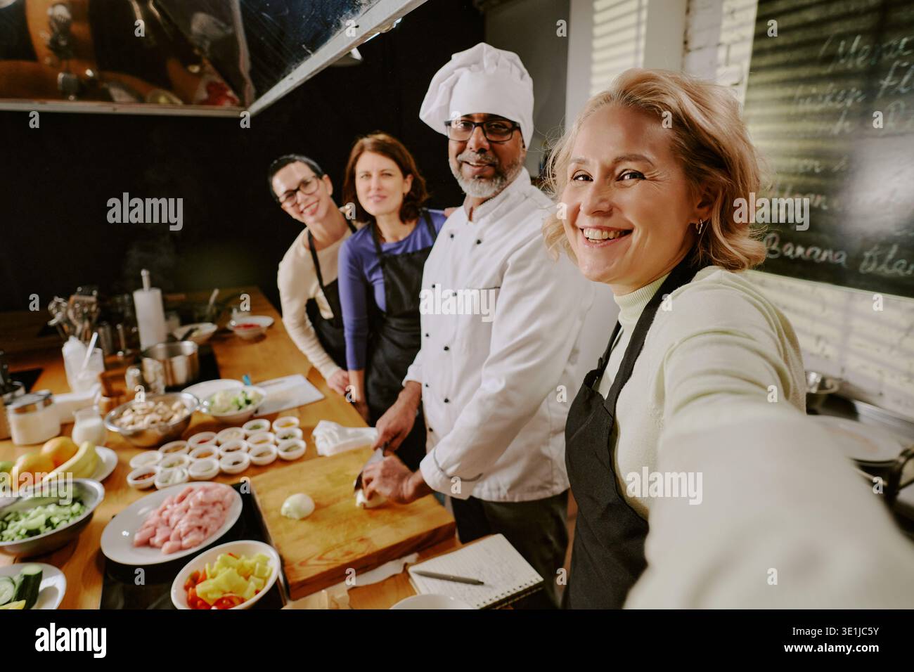 Gruppo eterogeneo di adulti di mezza età che partecipano alla lezione di cucina insieme sorridenti Foto Stock
