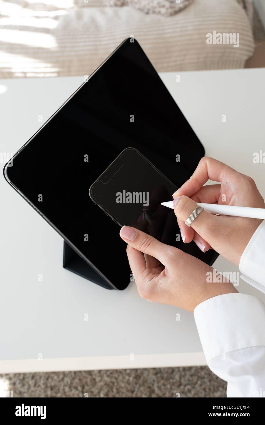 Mani femminili che disegnano su tablet con stilo mentre guardano smartphone: Arte digitale, flusso di lavoro tecnologico, tecnologia moderna Foto Stock