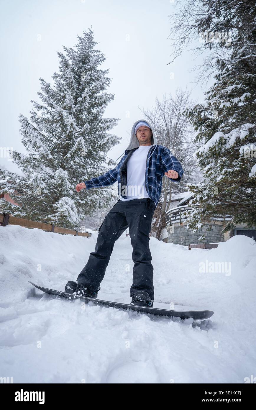 Lo snowboarder scivola davanti agli chalet di San Domenico, Alpi italiane Foto Stock